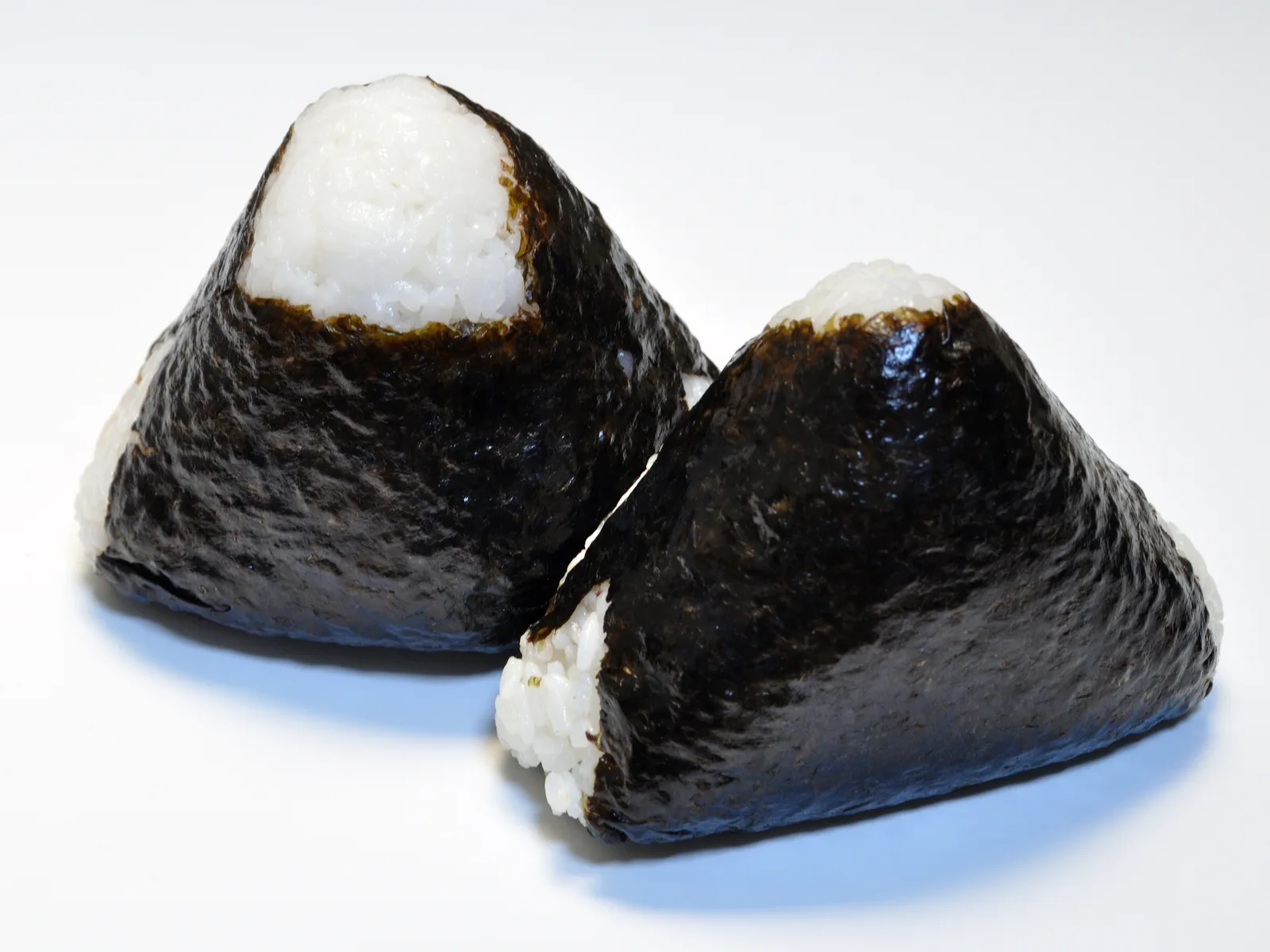 Twee driehoekige onigiri met een vel nori, op een bord
